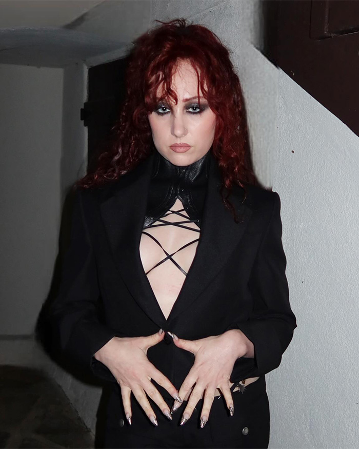 Chappell Roan wearing a black outfit with red hair, posing indoors amid luxury hotel security guard scandal developments. Chappell Roan wearing a black outfit with red hair, posing indoors amid luxury hotel security guard scandal developments.