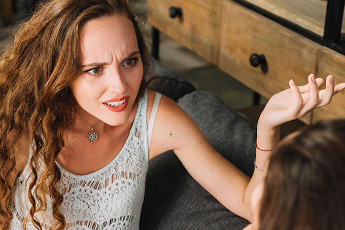 Mulher com cabelo comprido parecendo chateada e conversando com um amigo sobre cabelo bagunçado após mal-entendido no casamento.