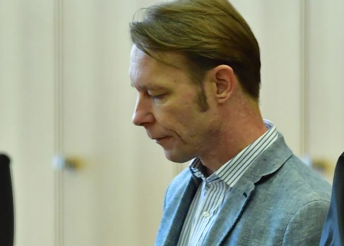 Man in a blue blazer with striped shirt looking down, related to major update in search for Madeleine McCann case