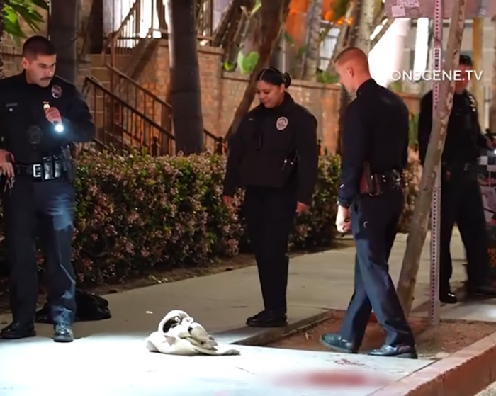 Police officers investigating a grisly scene in downtown LA after a man lost his life on the sidewalk at night.
