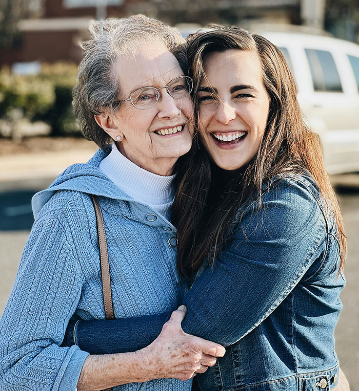 Elderly woman and young woman smiling and hugging outdoors, capturing a moment related to eerie and unexplained experiences.