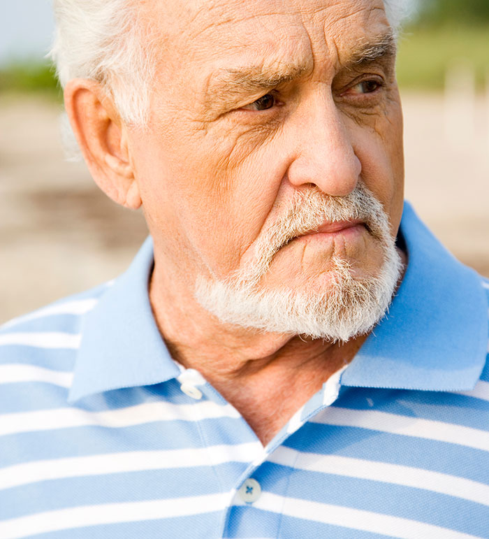 Elderly man with white beard and striped shirt looking pensively, reflecting on eerie and unexplained experiences.
