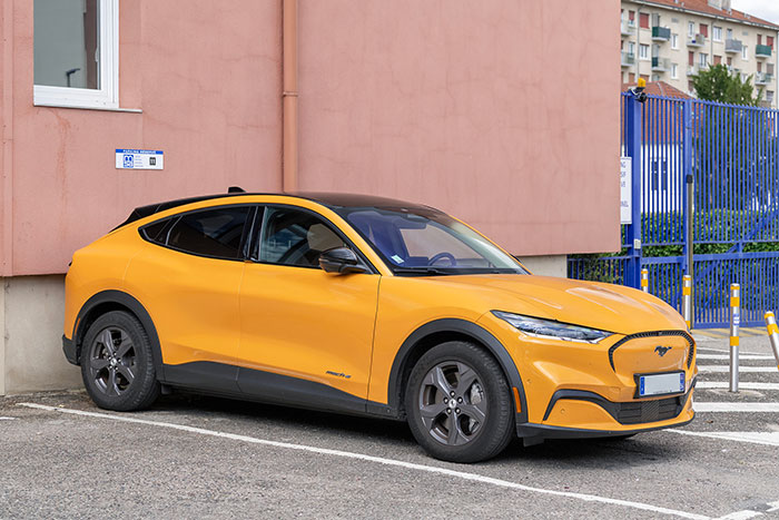 Yellow electric car parked by a pink building, illustrating eerie and odd stories about people experiencing unexplained things.