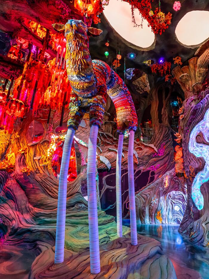 Vibrant surreal art installation with long-legged creature in a mysterious, eerie environment evoking unexplained experiences.