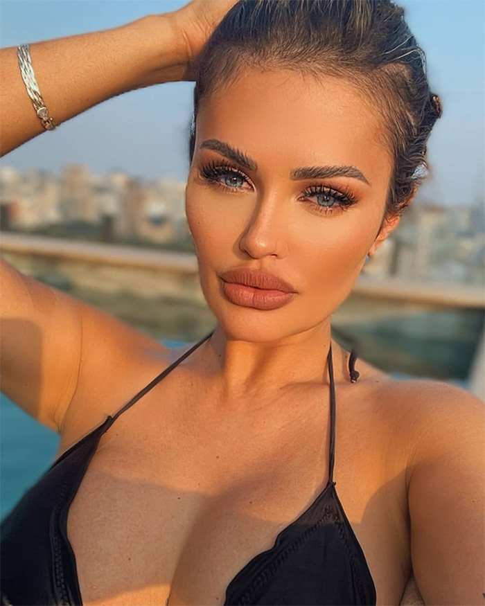 Influencer posing outdoors in a black top, addressing complaints and warning about inappropriate Disney World outfit controversy.