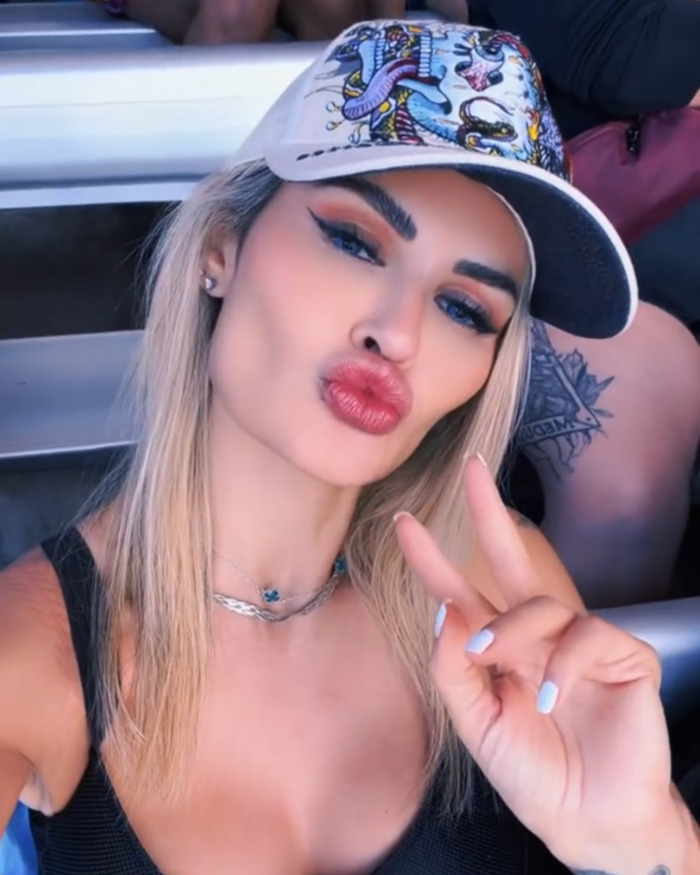 Influencer wearing a patterned cap and black top, making a peace sign, speaking out after Disney World outfit complaints.