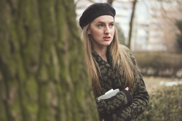 Young woman wearing a black beret and coat standing outdoors, symbolizing amazing women shutting down creepy advances.