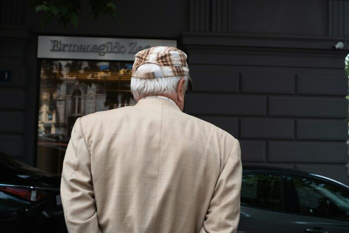 Elderly man wearing plaid cap and beige jacket standing outdoors, evoking mystery and unexplained phenomenon.