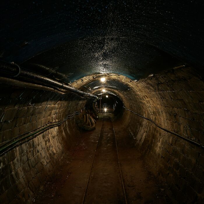 Dark underground tunnel with dim lights and damp walls, evoking some of the scariest experiences people still can't believe.