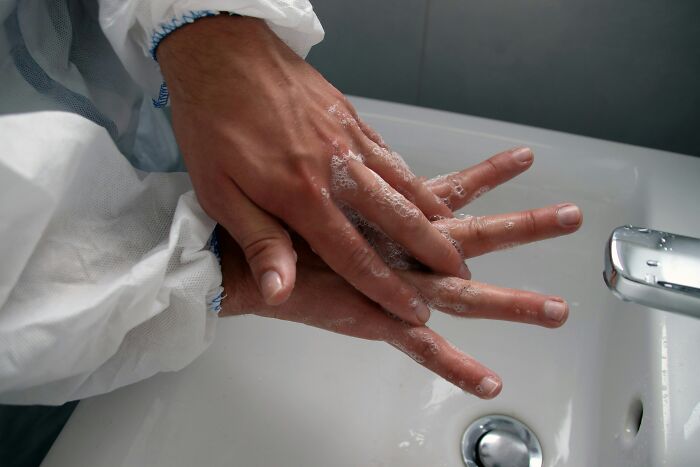 Person washing hands thoroughly with soap under a faucet, emphasizing hygiene and health practices.