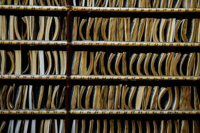 Rows of vintage, numbered folders on wooden shelves, evoking a mysterious urban explorer archive setting.