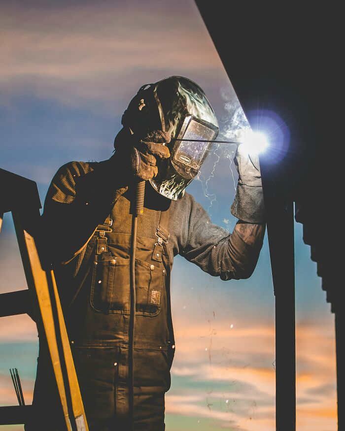 Welder working at sunset wearing protective gear, illustrating moments when people destroyed their own lives in an instant.