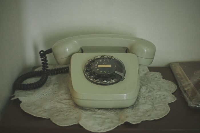 Vintage rotary telephone on lace doily, evoking mystery and unexplained phenomenon themes in an old setting.
