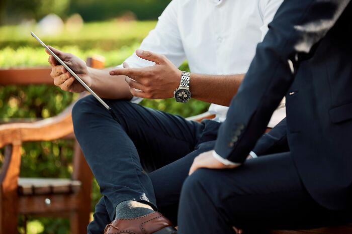 Two men in business attire having a serious conversation outdoors, illustrating regret and silence as the best option.