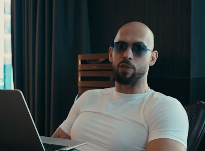 Man wearing sunglasses and white shirt sitting indoors with laptop, reflecting on dropping the red pill mindset.