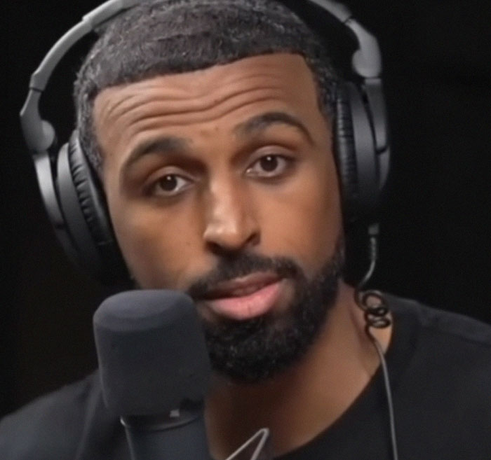 Man wearing headphones speaking into a microphone, sharing his moment dropping the red pill mindset in a podcast setting.