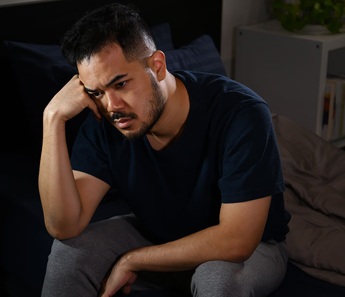 A man deep in thought, sitting on a bed, reflecting on the moment he dropped the red pill mindset.