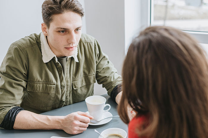 Young man in green jacket sharing a moment over coffee, reflecting on dropping the red pill mindset in a casual setting.
