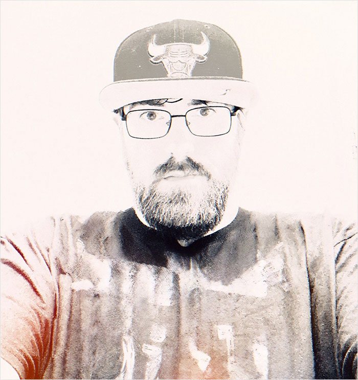 Man wearing glasses and a Chicago Bulls cap, representing owner of world's tiniest package in a high-contrast photo.