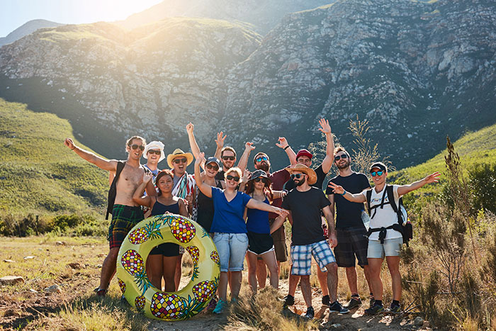 Group of friends posing outdoors on a sunny hike, capturing a moment before the MIL plans a spite trip after rejection.