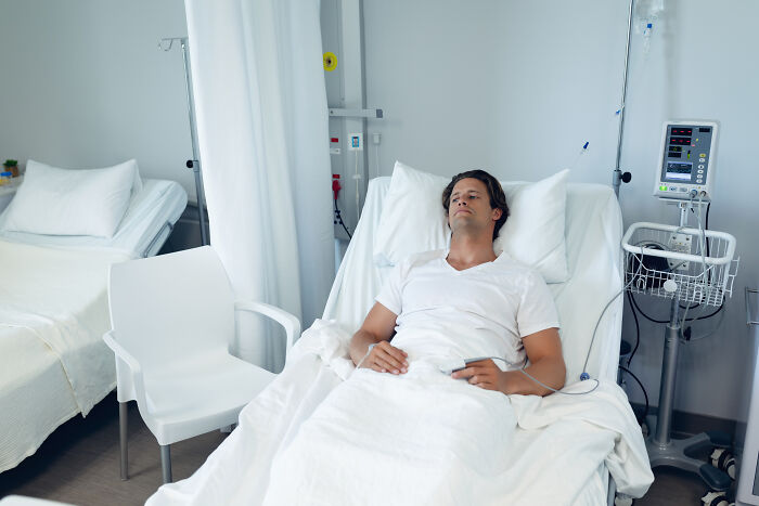 Patient resting in a hospital bed connected to medical equipment in a clinical setting, highlighting healthcare environment.