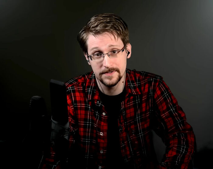Man wearing glasses and red plaid shirt speaking into microphone in a dark room about wild discoveries like this generation’s Moon landing