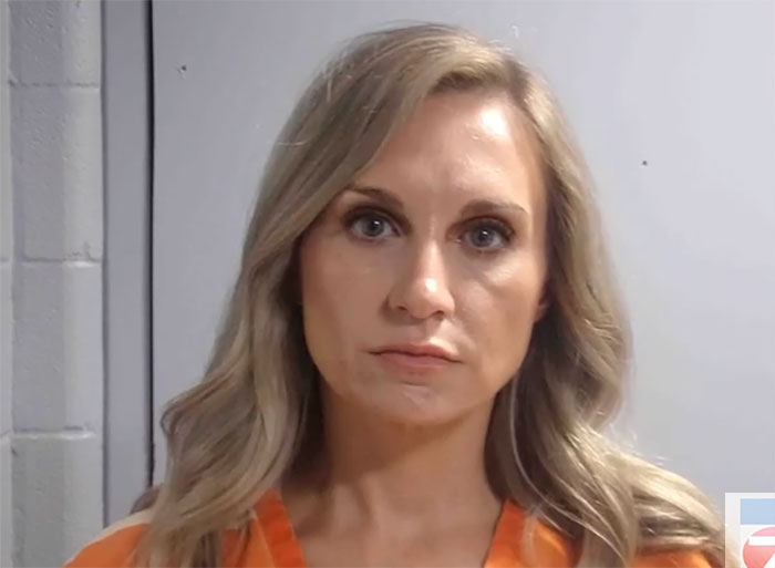 Former Louisiana mayor in an orange jumpsuit with blonde hair, pictured indoors against a gray wall background.