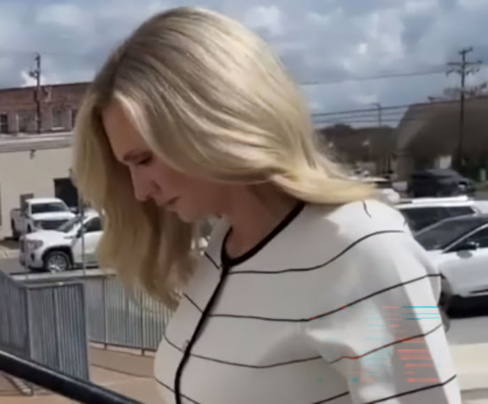 Former Louisiana mayor looking down outside near parked cars, reacting after getting caught at pool party incident.
