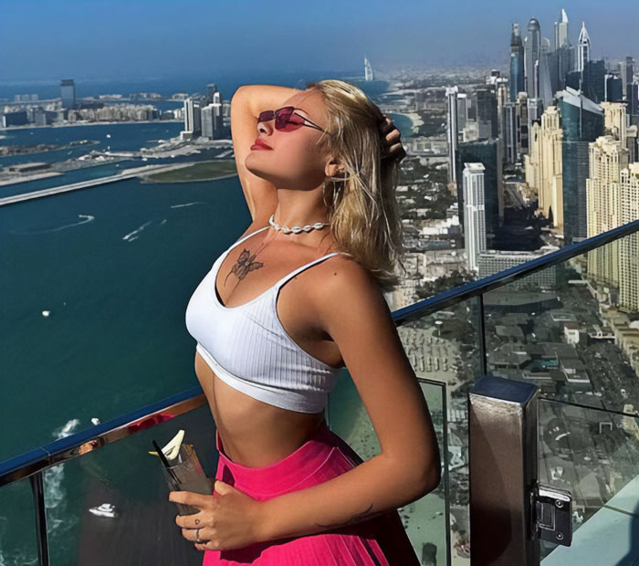 Model posing on Dubai rooftop with city skyline in the background, symbolizing her comeback after horrific injuries.