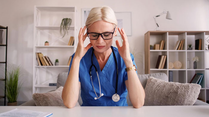 Stressed mom in scrubs balancing work and family, feeling overwhelmed with relationship and family responsibilities at home.