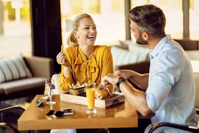 A man and woman share food at a restaurant table, showing friendly interaction before any nasty behavior appears.