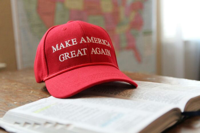 Red Make America Great Again hat resting on an open book, symbolizing controversial and nasty political opinions.