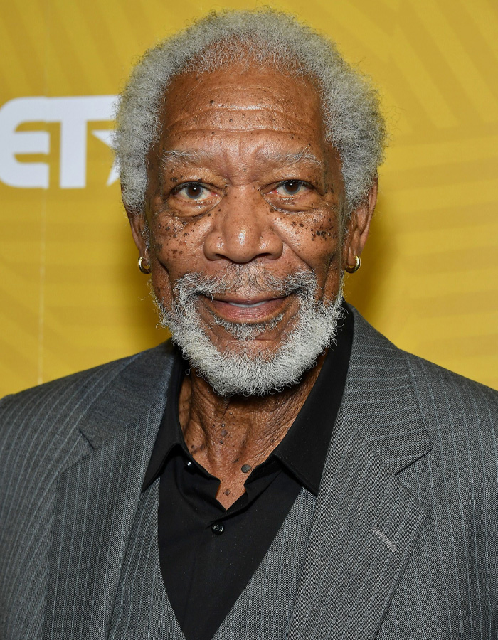 Morgan Freeman posing in a gray suit and black shirt, highlighting comments about Trump and his felonies in the spotlight.