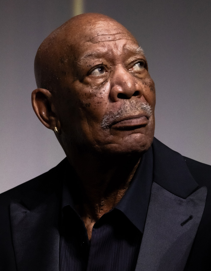 Morgan Freeman in a dark suit looking thoughtfully to the side, highlighting his comments on Trump's felonies.