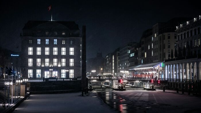 Nighttime cityscape showing illuminated buildings and a quiet canal, evoking bizarre encounters that leave folks questioning reality.