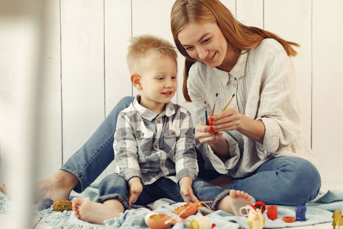 Woman watching ex&rsquo;s nephew and painting together at home, showing care despite recent breakup challenges.