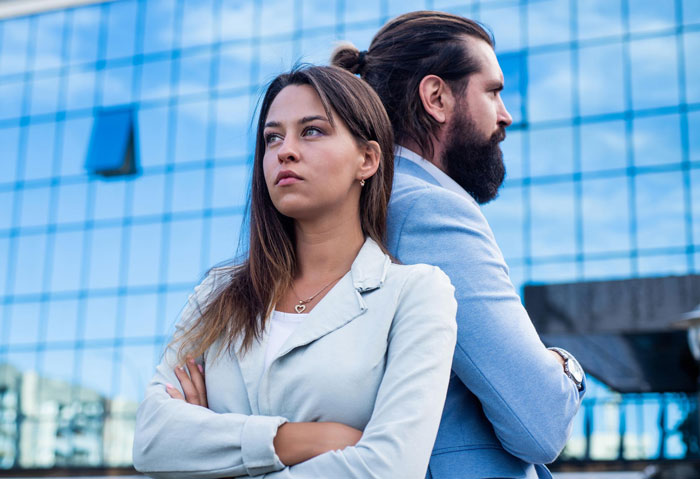 Woman and man standing back to back looking upset, representing breakup and unwanted family responsibilities.