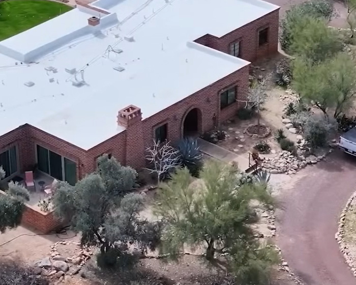 Aerial view of a desert-style brick house surrounded by trees, related to the mystery of gloves in Nancy Guthrie case.