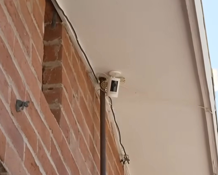 Security camera mounted on brick wall capturing footage relevant to FBI analysis of Nancy Guthrie case theories and leads.