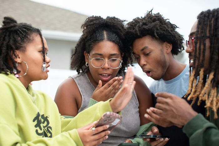 Four young people reacting with surprise and regret while looking at their smartphones, illustrating why shutting up was best.
