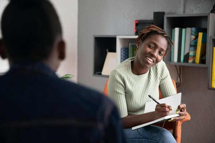 Two people in a casual meeting, one taking notes, representing shaky industries at risk of collapse if truths are revealed.