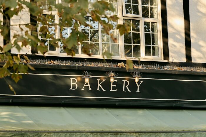 Exterior of an old building with a bakery sign, an eerie scene evoking terrifying urban explorers dropping flashlights.