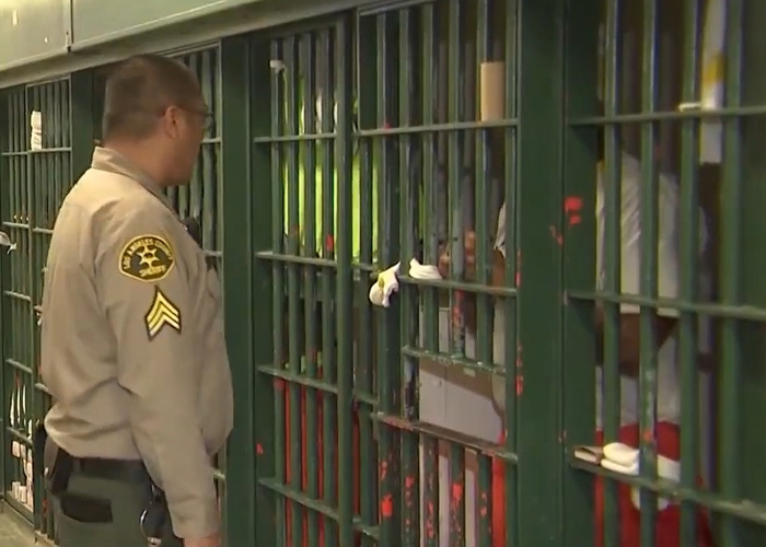 Jail officer standing beside a barred cell with inmates inside, highlighting disturbing talk and breaking point signs.