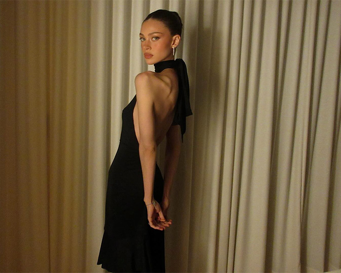 Nicola Peltz in a black backless dress posing indoors, with behavior called out as disturbing in birthday post.