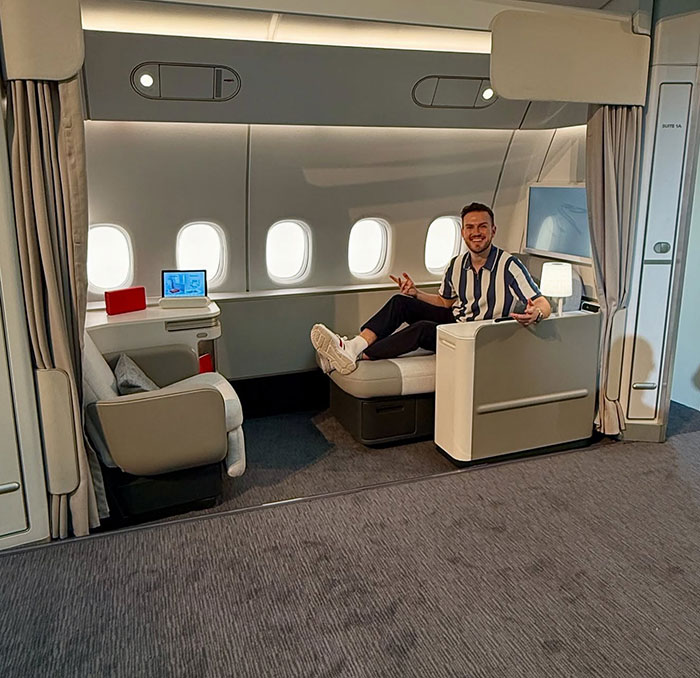 Man sitting comfortably in a spacious airplane suite, highlighting influencer refusing to fly economy during war travel issues.