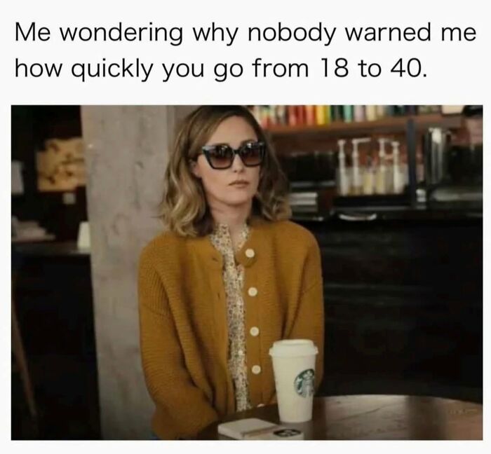 Woman in sunglasses and mustard cardigan sitting at a cafe, reflecting on aging, relatable to millennials' childhood nostalgia.