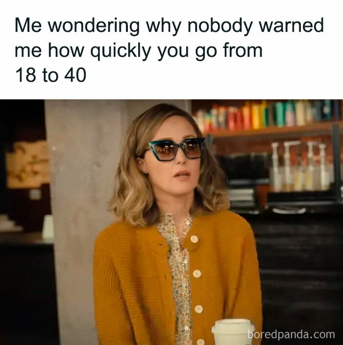 Woman in sunglasses and mustard cardigan sitting at a cafe, reflecting on aging, relatable to millennials' childhood nostalgia.