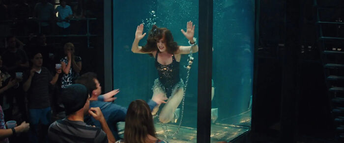 Woman chained underwater in a glass tank performing a dangerous escape stunt for a live audience, illustrating disturbing real life scenes.