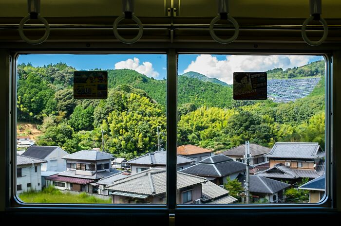 View of traditional houses and green hills through a train window highlighting culture shock experiences for foreigners.
