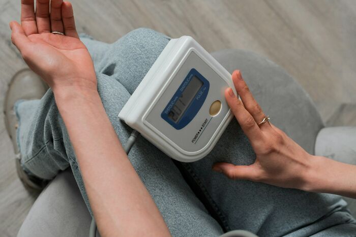 Person measuring blood pressure at home highlighting malfunctioning brain causing dumb ER visits problem